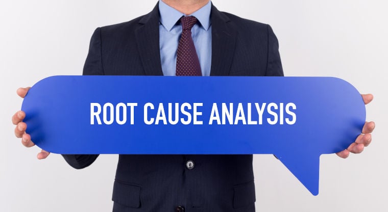 Geschäftsmann hält dunkelblaue Sprechblase mit der Aufschrift "Root Cause Analysis" in den Händen